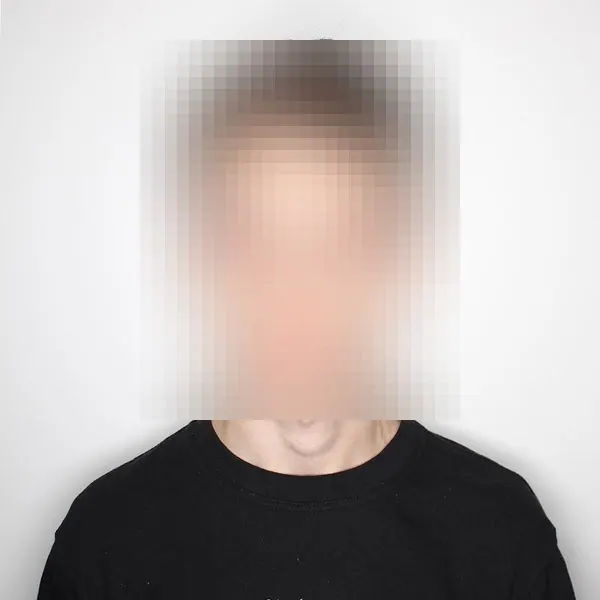 Portrait of Tim Derzhavets, face deliberately pixelated, black t-shirt on a light grey ground.
